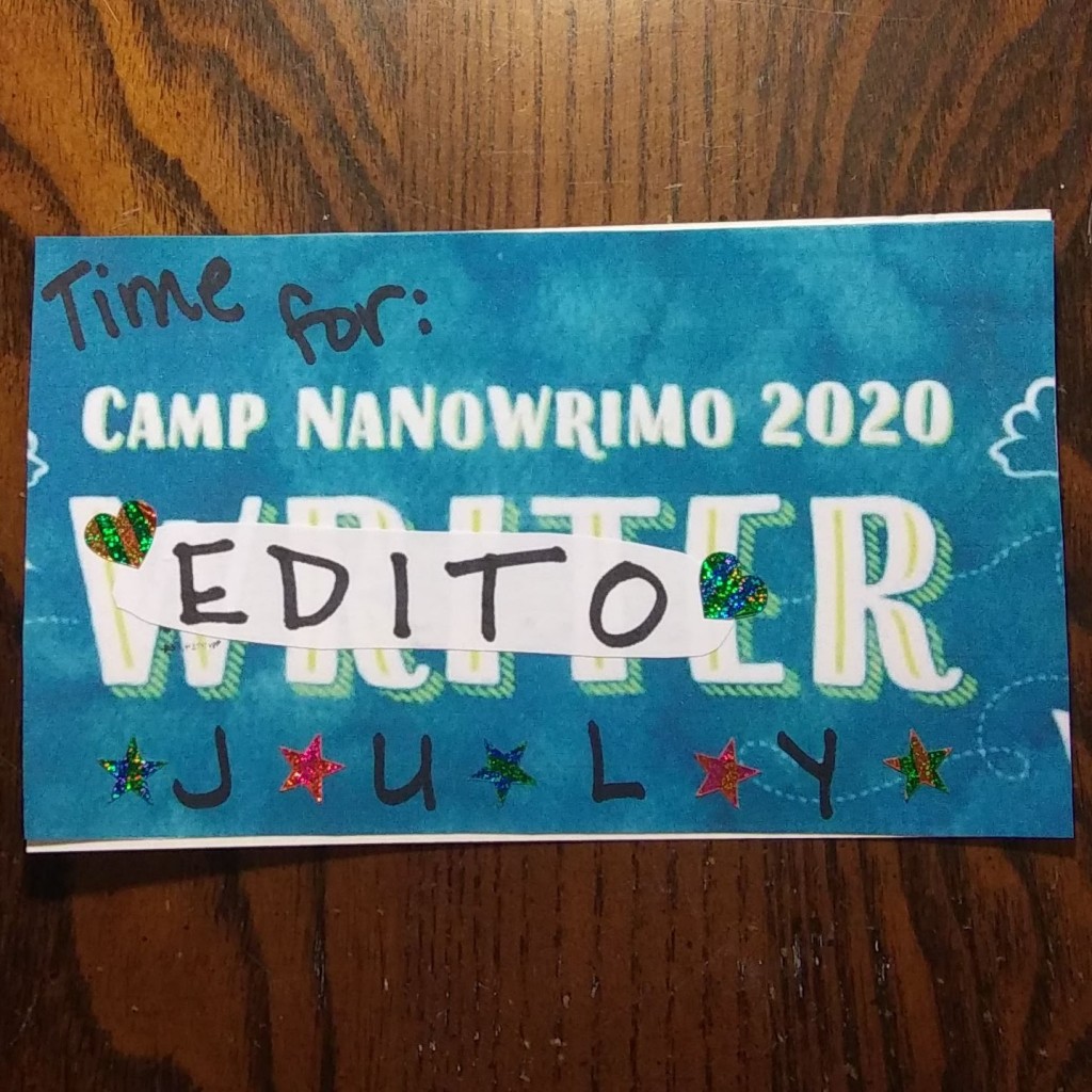An index card, with a blue background. The text says "Time for: Camp NaNoWriMo 2020. Writer. July". The word "writer" has been covered with a strip of white paper that has the word "editor" on it. The card is decorated with sparkly star stickers.